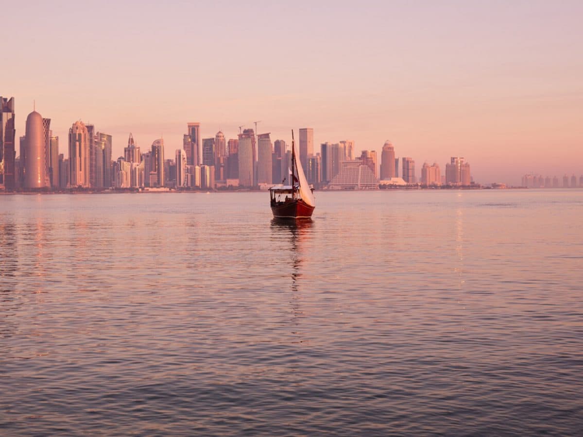 Traditional dhow sailing on Doha Bay with the West Bay skyline at sunset